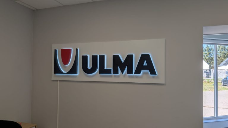 Podświetlane litery 3D ULMA z efektem halo na białej tablicy w recepcji